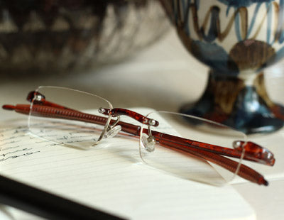 Pair of tortoise color rimless reading glasses sitting on a notebook