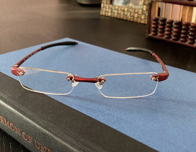 Red half eye lens reading glasses in red sitting on a book