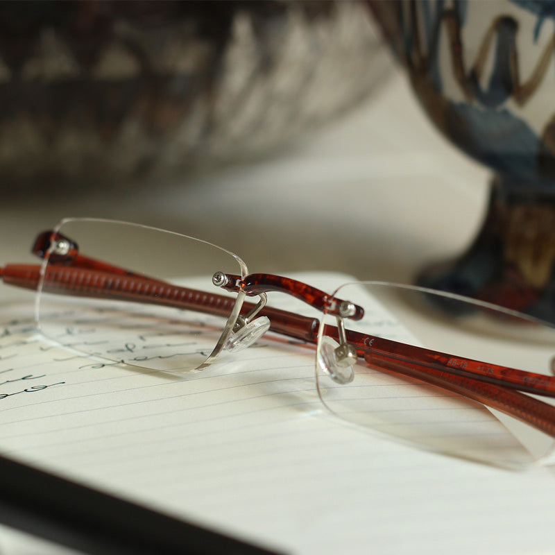 Pair of tortoise color quality rimless reading glasses sitting on a notebook
